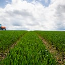 Tractor conduciendo a lo largo de campo de cultivo, vista lateral