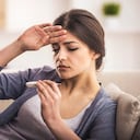 Mujer joven está mirando el termómetro. Ella tiene fiebre.