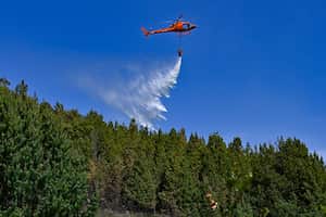 A helicopter drops water to put out a forest fire in Nemocon, Colombia on January 26, 2024. Yesterday Colombia asked the member countries of the United Nations for help to extinguish around thirty forest fires that are ravaging several regions and drowning the capital, Bogota, in smoke. (Photo by Luis ACOSTA / AFP)