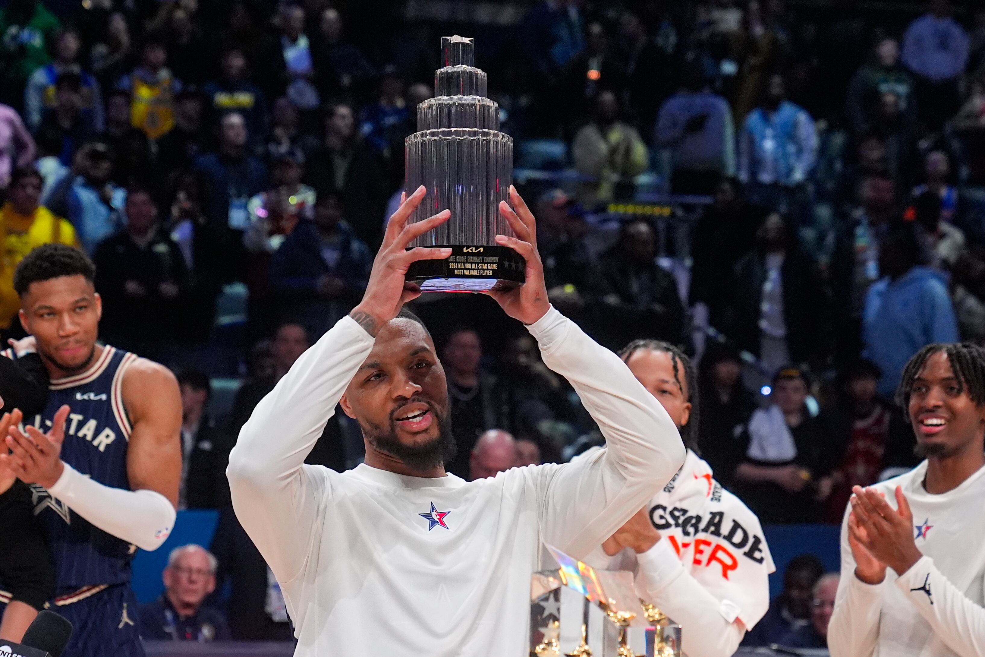 Milwaukee Bucks guard Damian Lillard (0) lifts the MVP trophy after the East defeated the West 211-186 in the NBA All-Star basketball game in Indianapolis, Sunday, Feb. 18, 2024. (AP Photo/Darron Cummings)