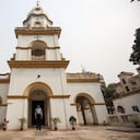En esta imagen tomada el 11 de febrero de 2021, el devoto hindú Shankar Ghosh posa para una foto frente a una iglesia armenia en Dhaka. - Haciendo la señal de la cruz en el pecho, el devoto hindú Shankar Ghosh abre las pesadas puertas de madera de una centenaria iglesia armenia mientras los primeros rayos de sol iluminan el edificio blanco y amarillo en Dhaka, la capital de Bangladesh. Foto de Rehman Asad / AFP