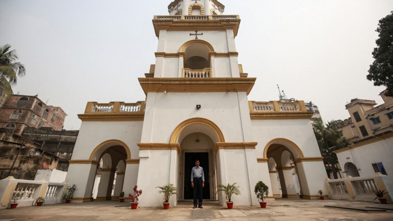 En esta imagen tomada el 11 de febrero de 2021, el devoto hindú Shankar Ghosh posa para una foto frente a una iglesia armenia en Dhaka. - Haciendo la señal de la cruz en el pecho, el devoto hindú Shankar Ghosh abre las pesadas puertas de madera de una centenaria iglesia armenia mientras los primeros rayos de sol iluminan el edificio blanco y amarillo en Dhaka, la capital de Bangladesh. Foto de Rehman Asad / AFP