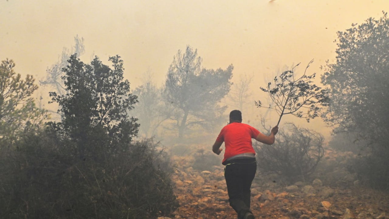 Los lugareños ayudan a los bomberos mientras intentan extinguir un incendio forestal que arde cerca del pueblo Vlyhada cerca de Atenas el 19 de julio de 2023 en Atenas, Grecia.