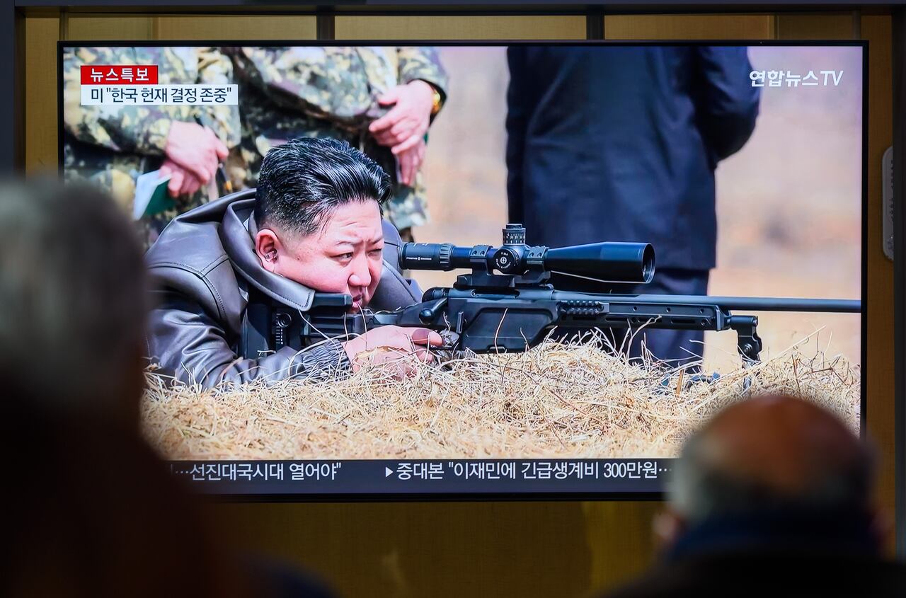 Personas observan una transmisión 24 horas del canal de noticias Yonhap desde la estación de tren de Seúl, donde se ve al líder norcoreano Kim Jong-un mirando a través de la mira de un rifle
