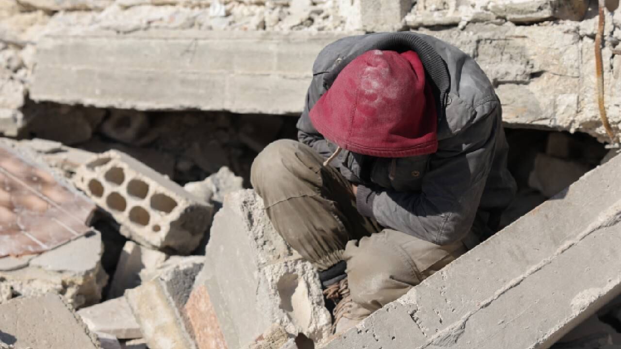 Un hombre sirio, en medio de los escombros, espera noticias sobre los miembros de su familia atrapados (referencia de uno de los damnificados por el terremoto).