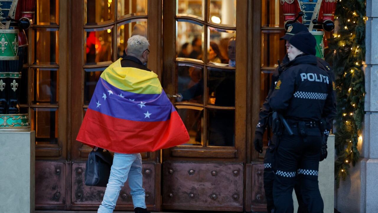 Policías observan cómo un hombre envuelto en una bandera venezolana entra al Grand Hotel de Oslo el 9 de diciembre de 2025, un día antes de la ceremonia de entrega del Premio Nobel de la Paz en la capital noruega