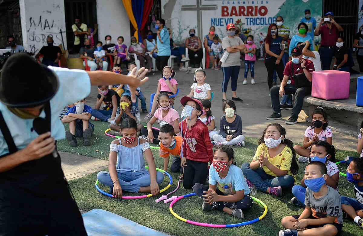 Los niños disfrutan de una actuación de la Fundación Nacional de Circo de venezuela, en el Barrio San Juan de Caracas, el 9 de mayo. El circo también transmite actuaciones en el teatro Nacional de Caracas, durante el cierre para evitar la propagación del virus. Foto: Matias Delacroix / AP. 