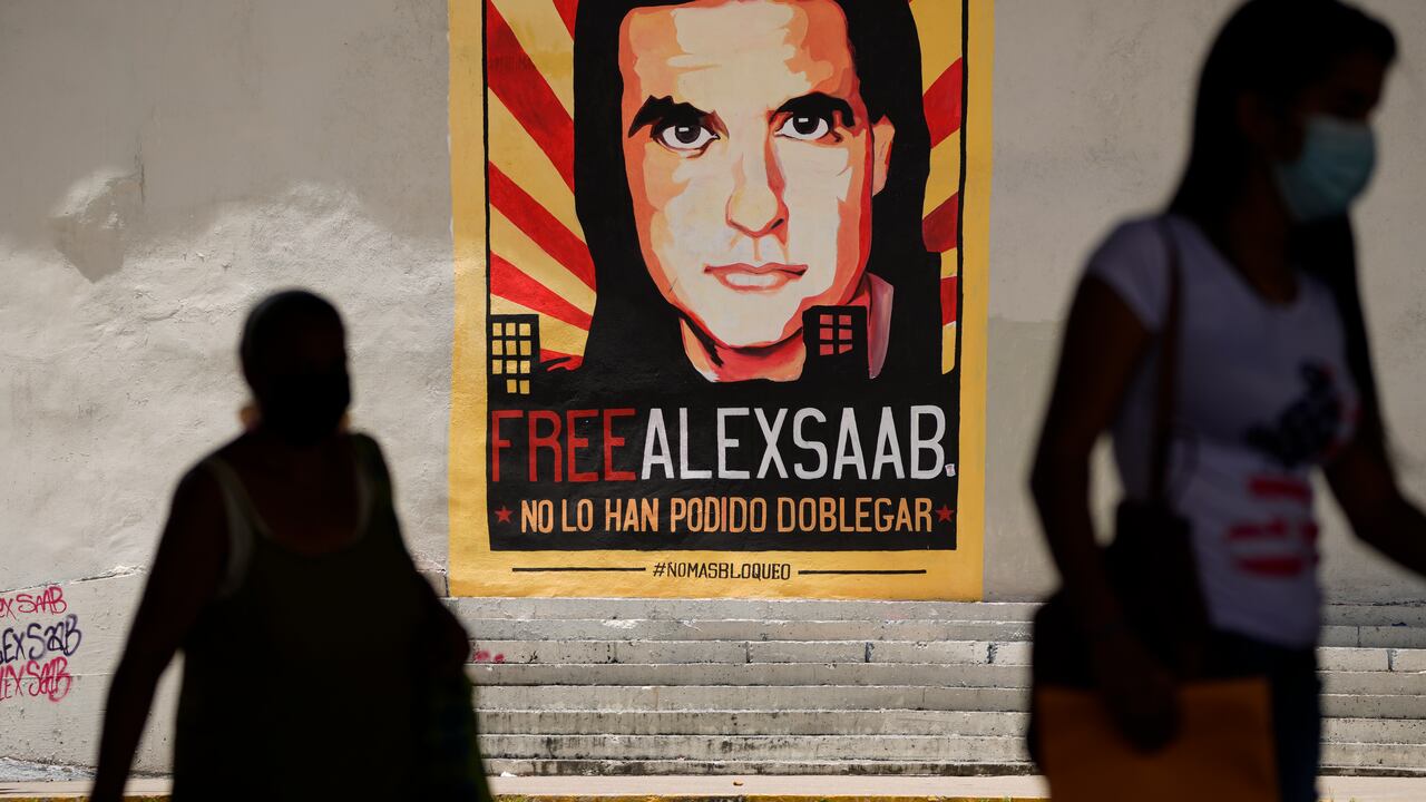 ARCHIVO - Imagen de archivo del jueves 9 de septiembre de 2021: personas caminaN cerca de un cartel que pide la liberación del empresario colombiano y enviado especial del gobierno venezolano, Alex Saab, en Caracas, Venezuela. (AP Foto/Ariana Cubillos, archivo)