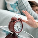 Mujer despertando con reloj despertador