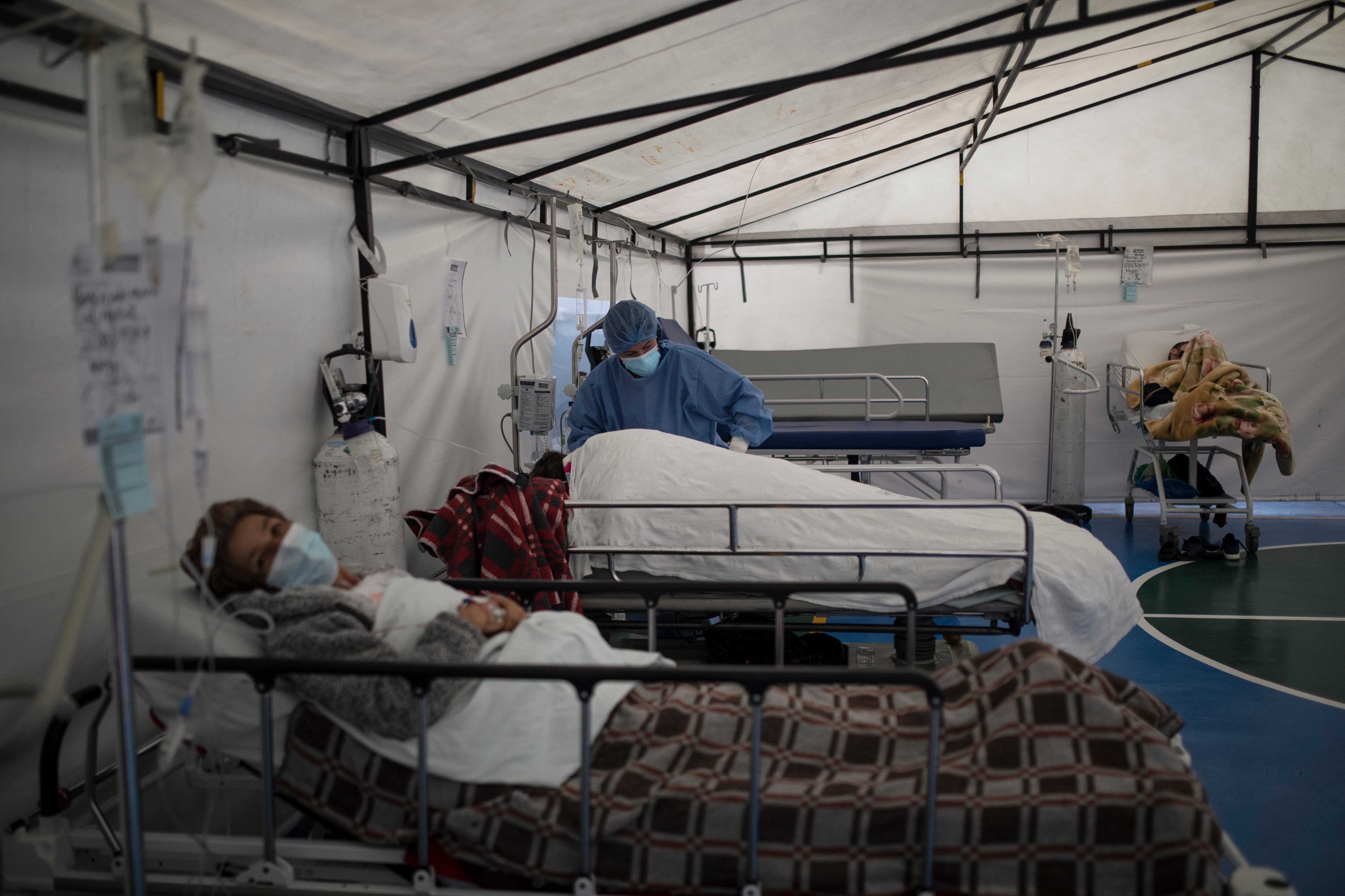 Un trabajador de la salud atiende a un paciente con COVID-19 en una carpa instalada en la cancha de fútbol del Hospital Samaritana, en Bogotá. (Foto AP / Ivan Valencia)
