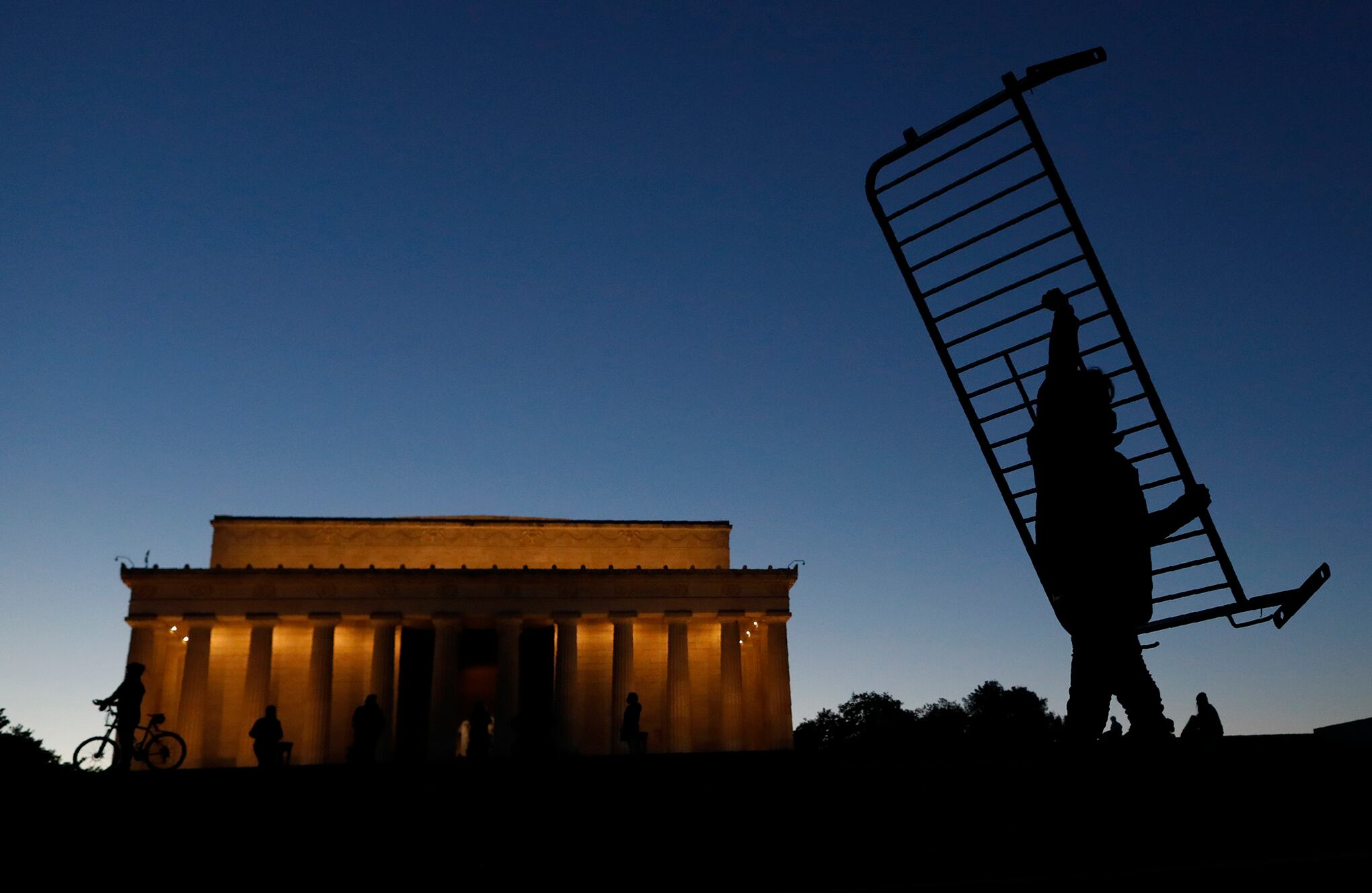 Un trabajador mueve una barrera de metal en el Lincoln Memorial mientras se desmantelan las instalaciones un día después de la toma de posesión del presidente Joe Biden, el jueves 21 de enero de 2021 en Washington. (Foto AP / Rebecca Blackwell)