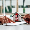 Los clientes interesados en comprar una casa firman una firma para celebrar un contrato de compra de vivienda con un agente inmobiliario. Aprobación de préstamo hipotecario préstamo hipotecario y concepto de seguro.
