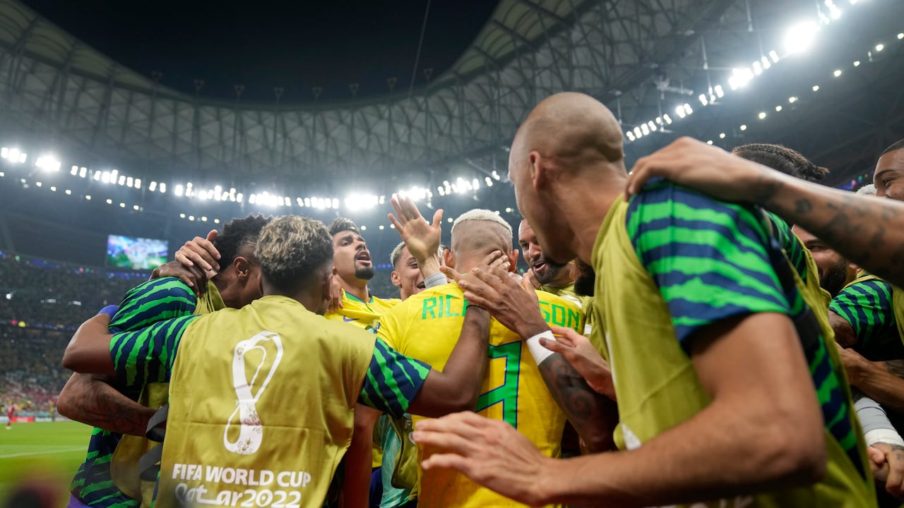 Brazil's Richarlison, center with back to camera, is congratulated by his teammates after scoring the opening goal during the World Cup group G soccer match between Brazil and Serbia, at the Lusail Stadium in Lusail, Qatar, Thursday, Nov. 24, 2022. (AP Photo/Andre Penner)