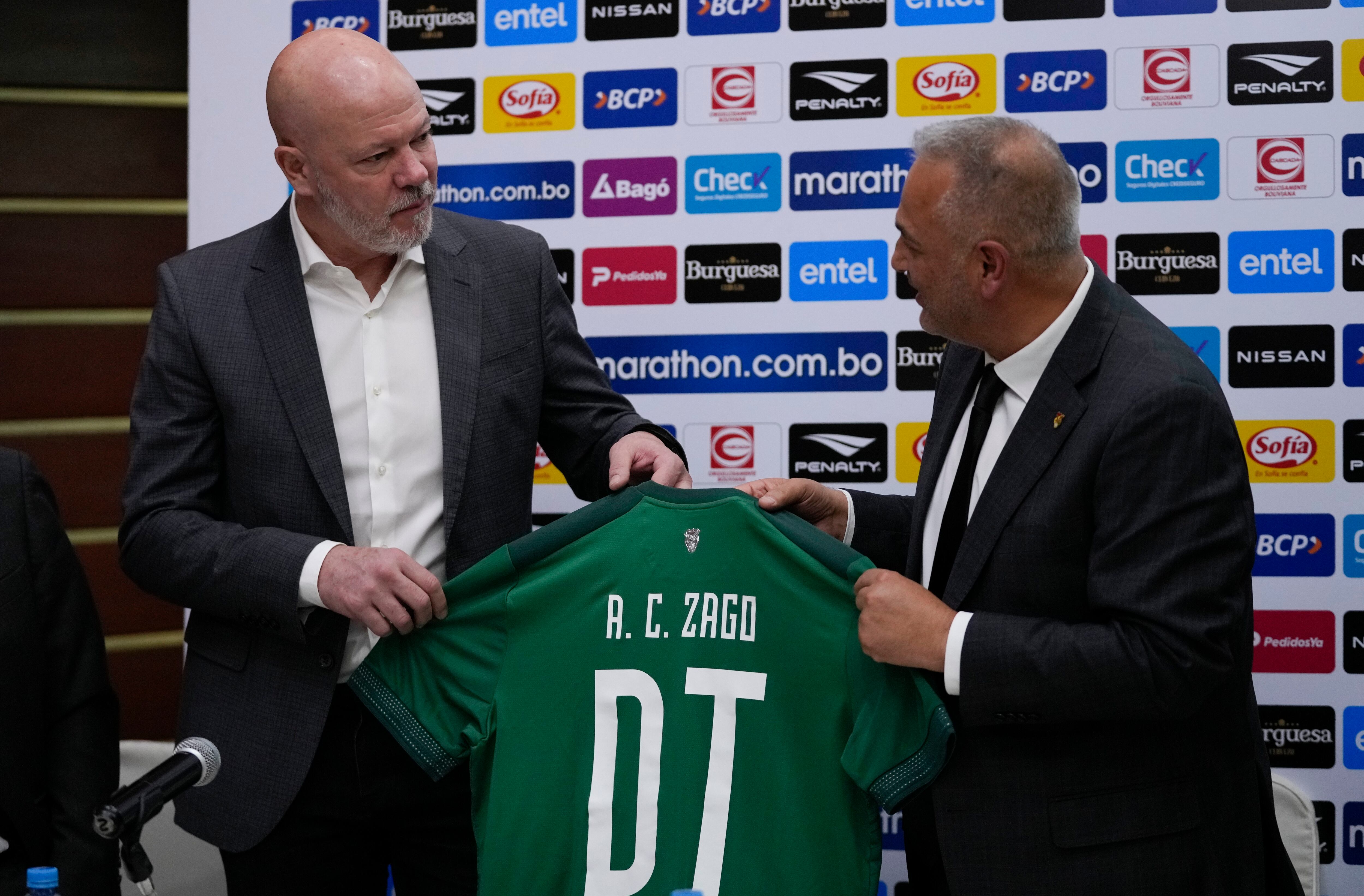Antonio Zago, de Brasil, a la izquierda, recibe su camiseta de manos del presidente de la Federación Boliviana de Fútbol, Fernando Costa, durante una ceremonia de firma en la que fue nombrado nuevo entrenador en jefe de la selección nacional de fútbol de Bolivia en La Paz, Bolivia, el martes 31 de octubre de 2023. ( Foto AP/Juan Karita)