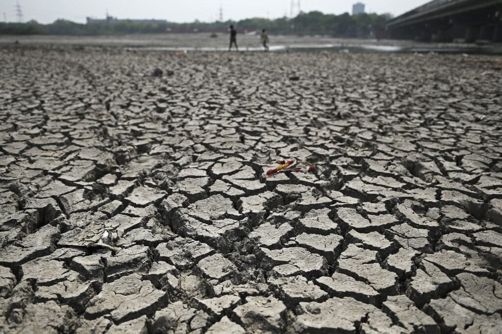 La gente camina por un tramo del lecho reseco del río Yamuna en un caluroso día de verano en Nueva Delhi el 2 de mayo de 2022. - (Foto de Sajjad HUSSAIN / AFP)