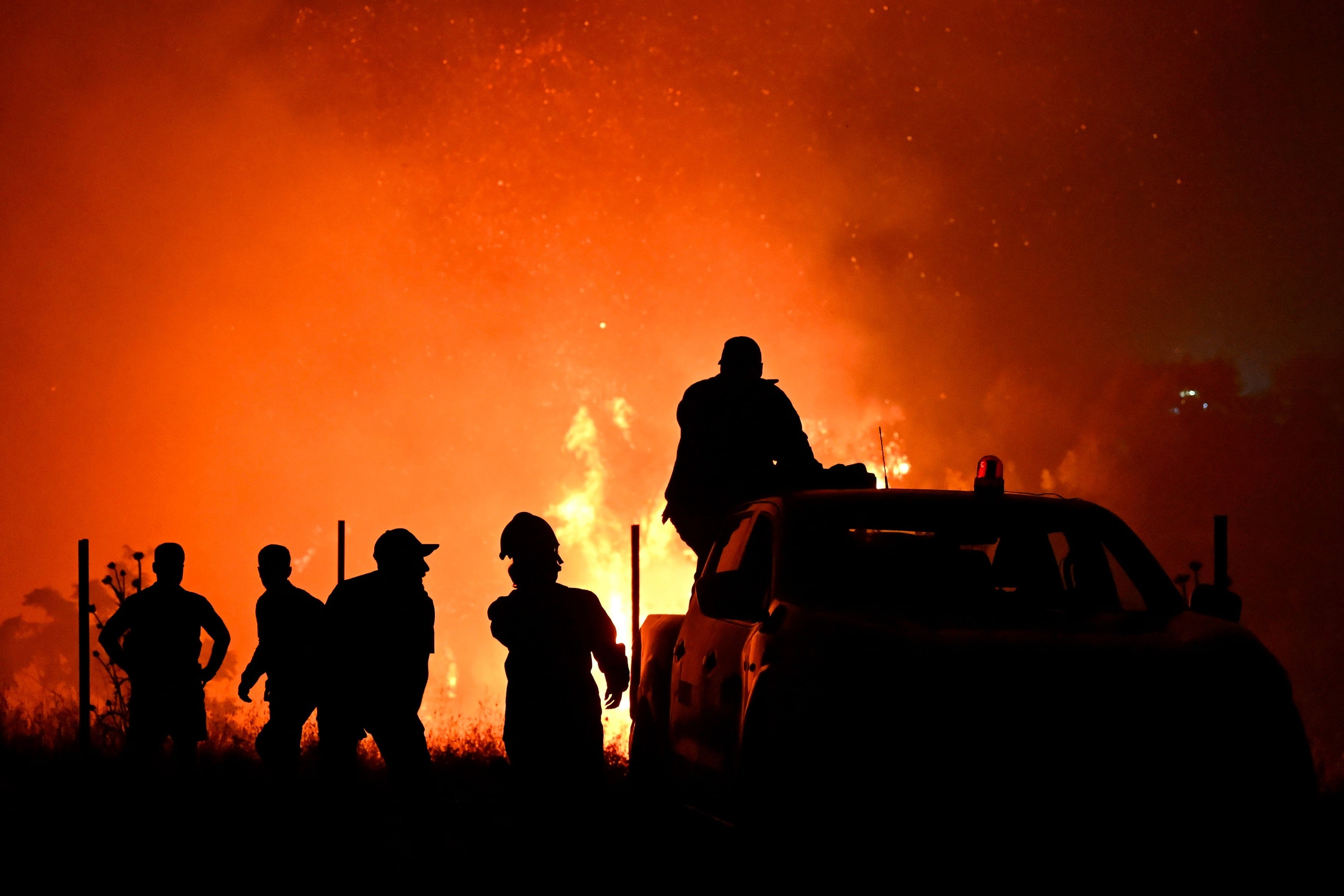 Las siluetas de bomberos y otras personas pueden captarse en medio de un incendio forestal el sábado 4 de julio de 2026, en las afueras de la ciudad de Salónica, en el norte de Grecia.