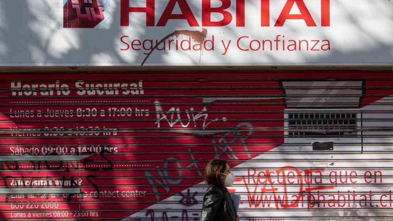 Una mujer pasa en frente de la oficina de una AFP en Santiago. Ciudadanos vandalizaron algunos locales, pidiendo el fin de los fondos privados. Foto: AFP