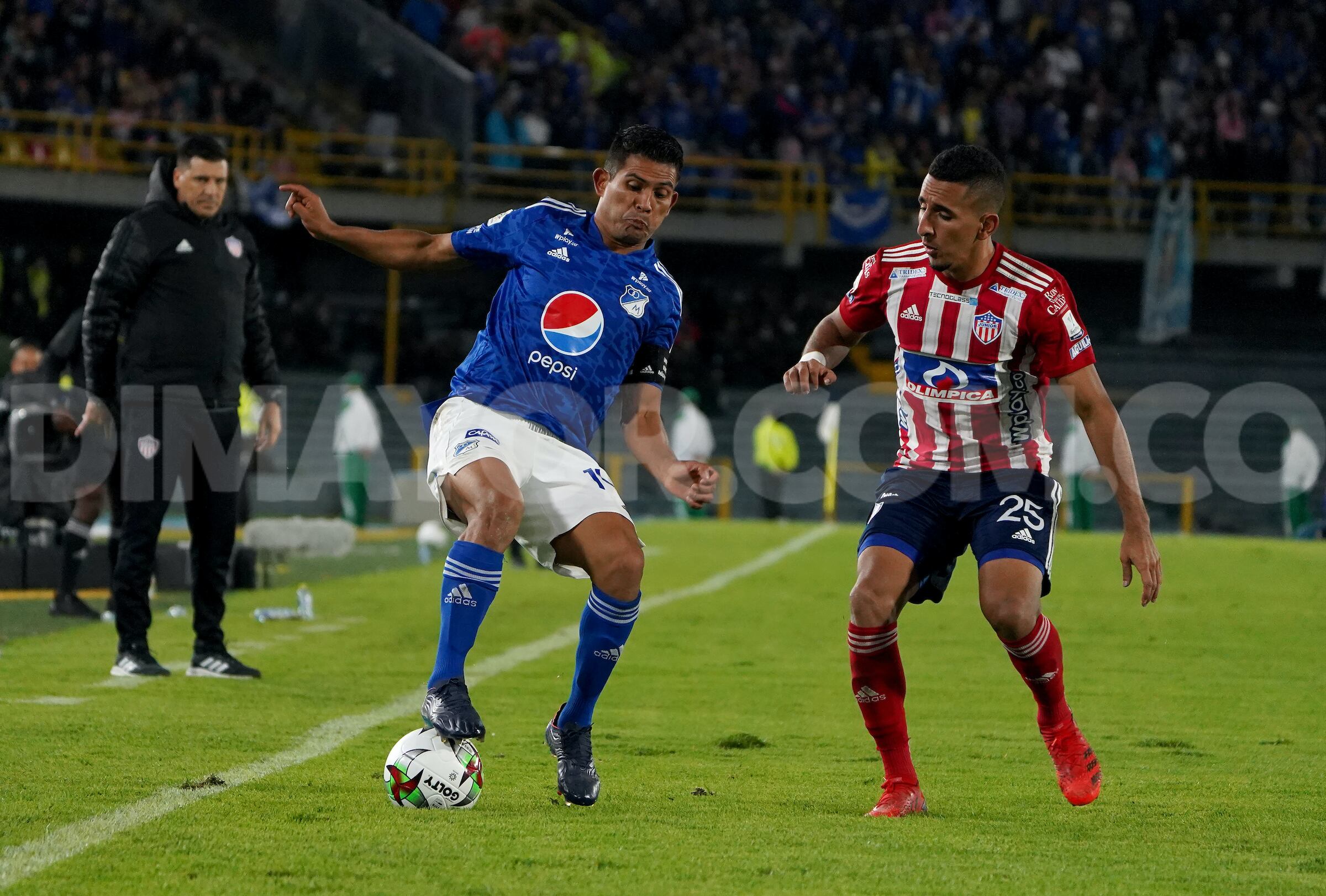 Macalister Silva (Millonarios) conduce el balón bajo la presión de Carlos Andrés Esparragoza (Junior)