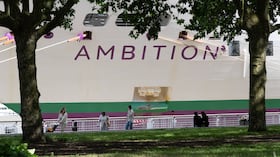 La gente pasa junto al crucero británico Ambition mientras las autoridades francesas ordenaron a 1.700 pasajeros y tripulantes permanecer a bordo debido a un brote de enfermedad gastrointestinal, en Burdeos, suroeste de Francia, el miércoles 13 de mayo de 2026