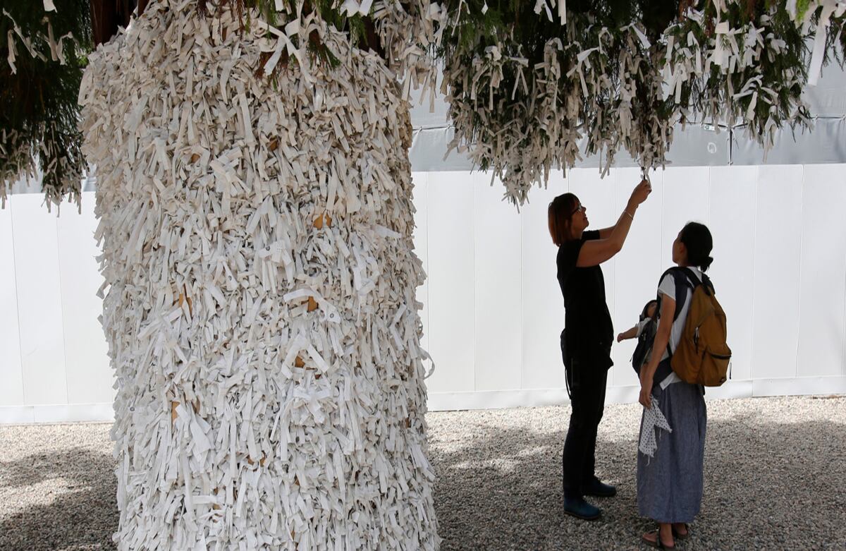 Una familia en Japón ata oráculos escritos a una rama de un árbol en el Gran Santuario de Izumo. El templo está dedicado a la deidad del matrimonio. (AP)