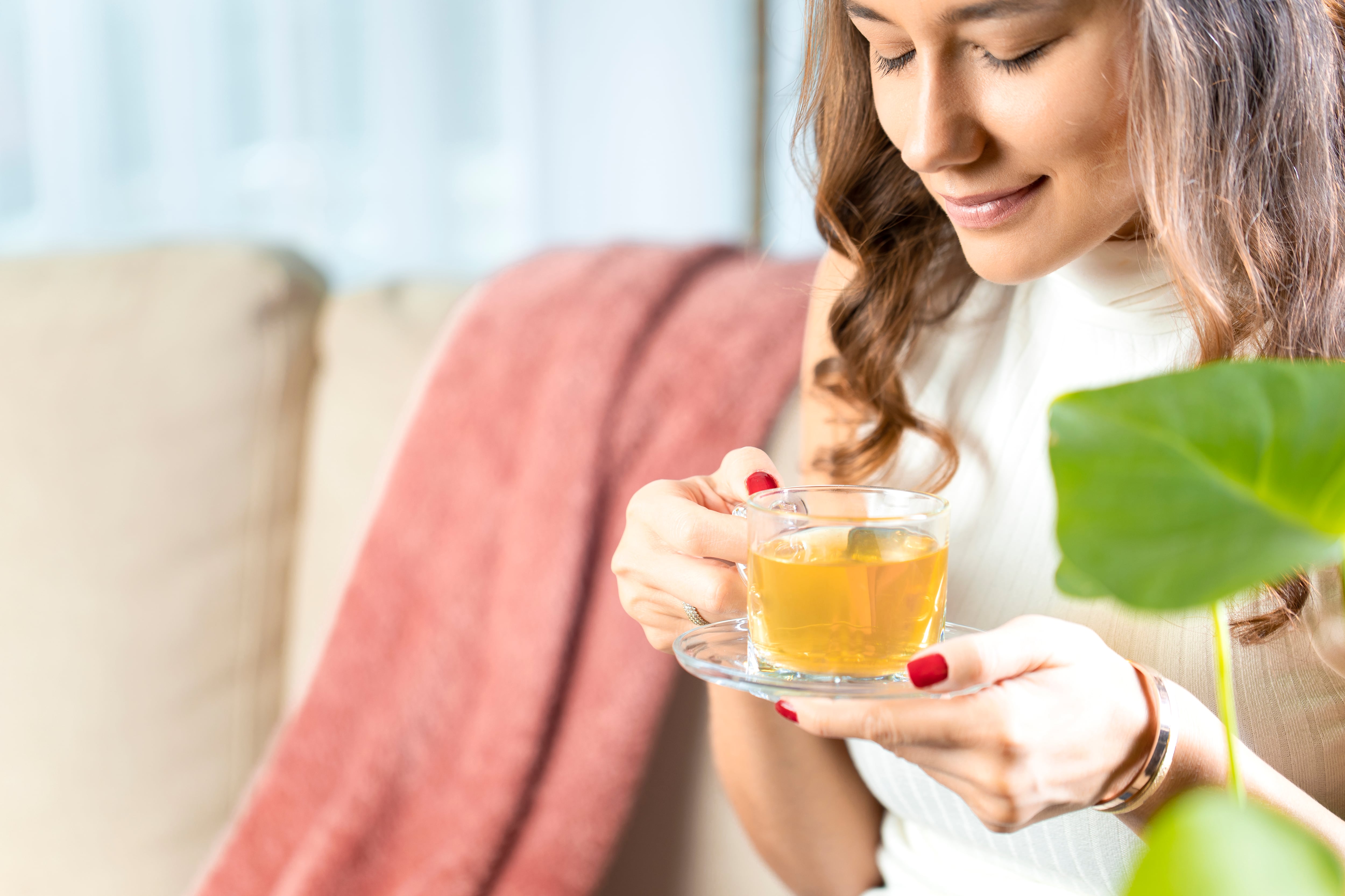 Beautiful young woman drinking hot tea in living room