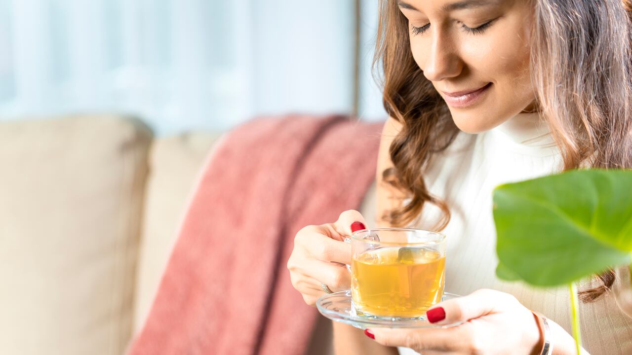 Beautiful young woman drinking hot tea in living room
