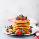 Comida y bebida, naturaleza muerta, concepto de nutrición saludable. Pila de panqueques caseros para el desayuno con bayas y azúcar. Fondo claro de la cocina del espacio de la copia