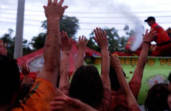 Tras la tomatina, los bomberos echan agua para limpiar a quienes soportaron más de media hora de guerra con tomates