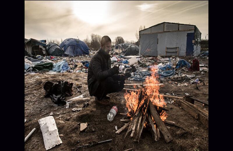 Hemn, un inmigrante kurdo, se calienta con una fogata en la "Jungla". Foto: Philippe Huguen / AFP