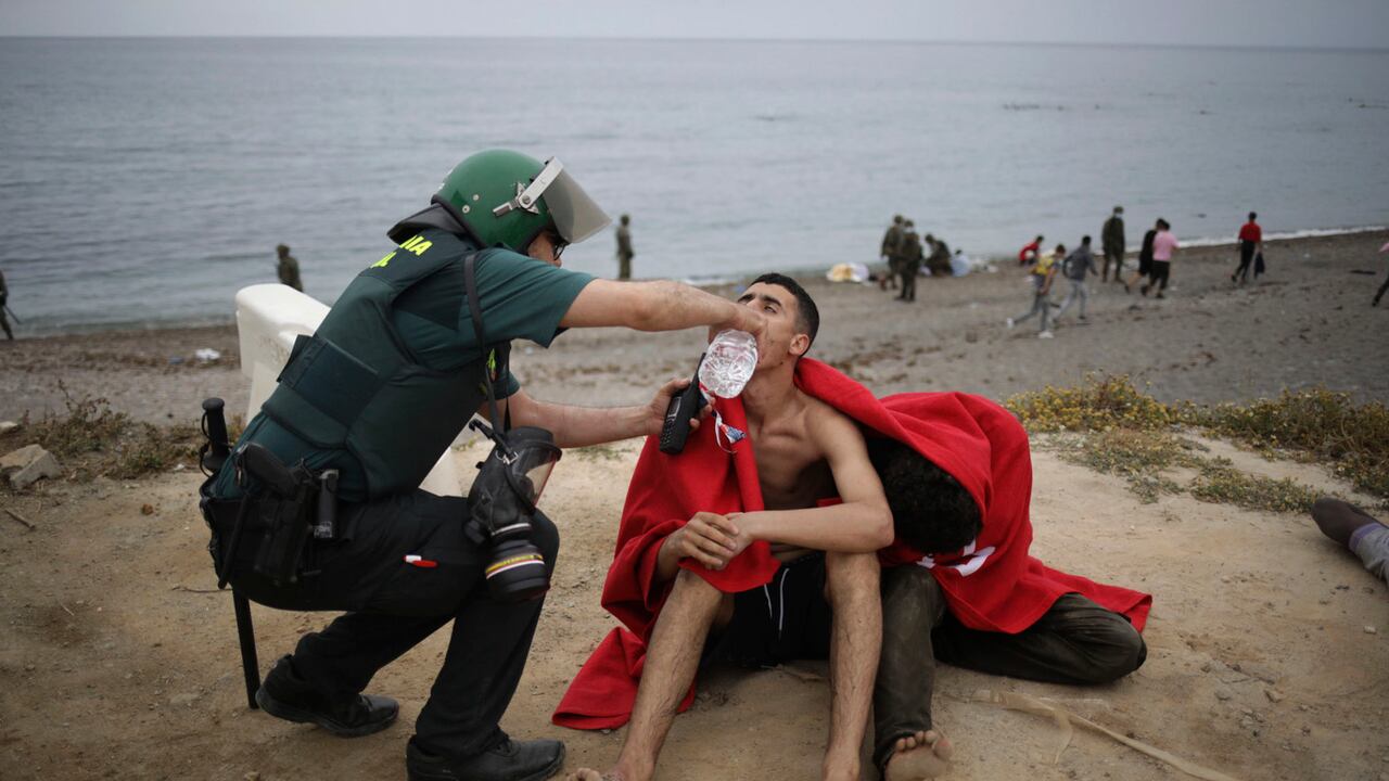Un hombre de Marruecos es asistido por un oficial de la Guardia Civil cuando llega nadando al enclave español de Ceuta, el martes 18 de mayo de 2021. Ceuta, una ciudad española de 85.000 habitantes en el norte de África, enfrenta una crisis humanitaria después de que miles de marroquíes tomaran ventaja de un control fronterizo relajado en su país para nadar o remar en botes inflables en suelo europeo. Alrededor de 6.000 personas habían cruzado el martes por la mañana desde que comenzaron las primeras llegadas en la madrugada del lunes, incluidas 1.500 que se presume son adolescentes. Foto: AP / Javier Fergo.