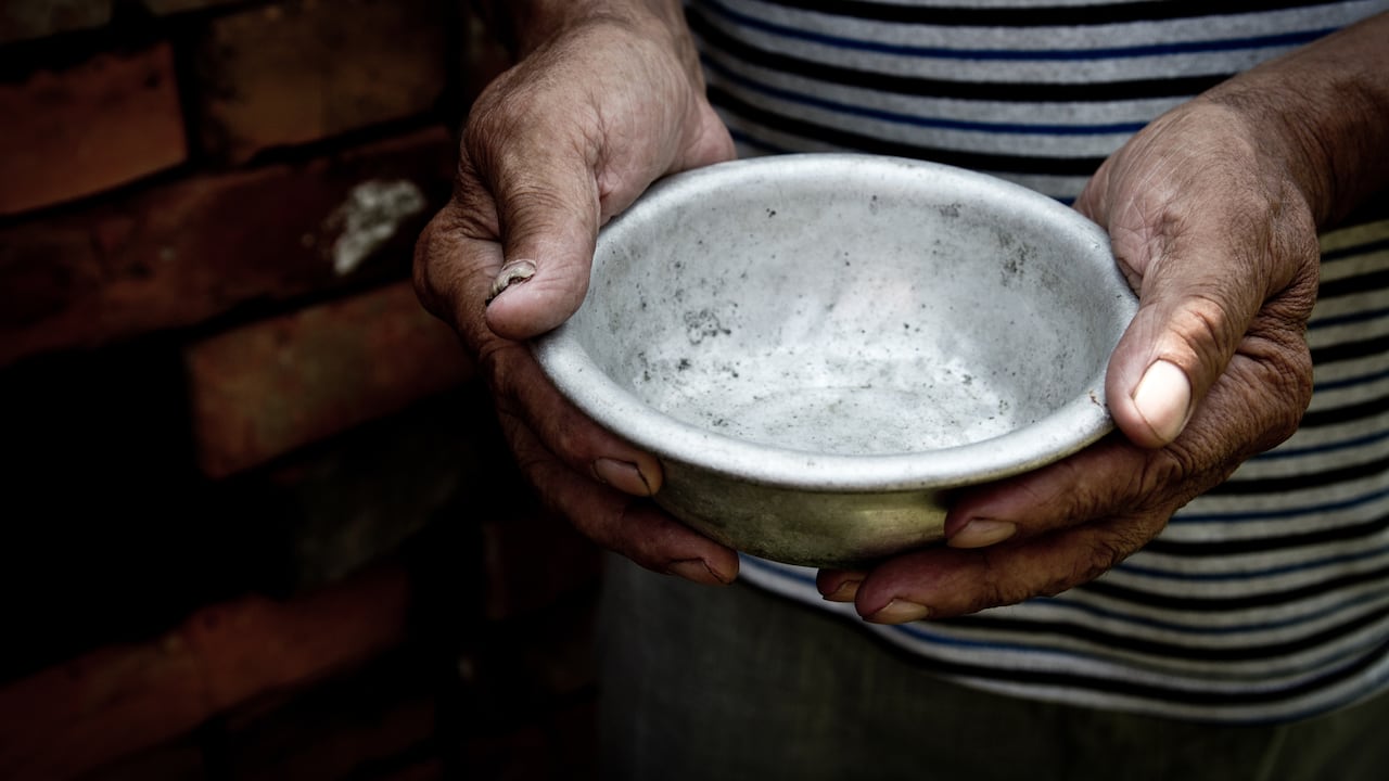 Las manos del pobre anciano sostienen un cuenco vacío
