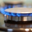 Imagen macro de encimera de gas en plena llama. Concéntrese en el frente del quemador y el encendedor a la izquierda de la llama.