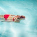 Mujer nadando bajo el agua en la piscina al aire libre