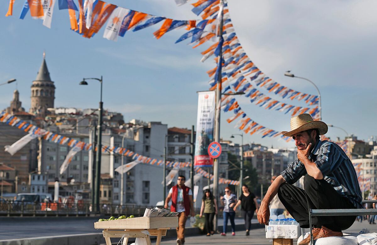 Un vendedor ambulante espera a sus clientes frente a la icónica Torre de Gálata y un fondo adornado por las banderas de la propaganda de las próximas elecciones generales en Estambul, Turquía. (AP/Emrah Gurel)