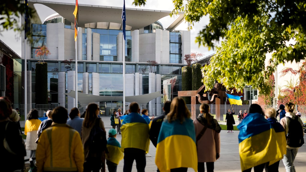 Personas con banderas ucranianas asisten a una protesta contra la guerra en Ucrania frente a la cancillería en Berlín, Alemania, el martes 11 de octubre de 2022. El canciller alemán Olaf Scholz organiza una reunión de los líderes del G7 con el presidente ucraniano Volodymyr Zelenskyy sobre la situación en Ucrania. (AP Photo/Markus Schreiber)