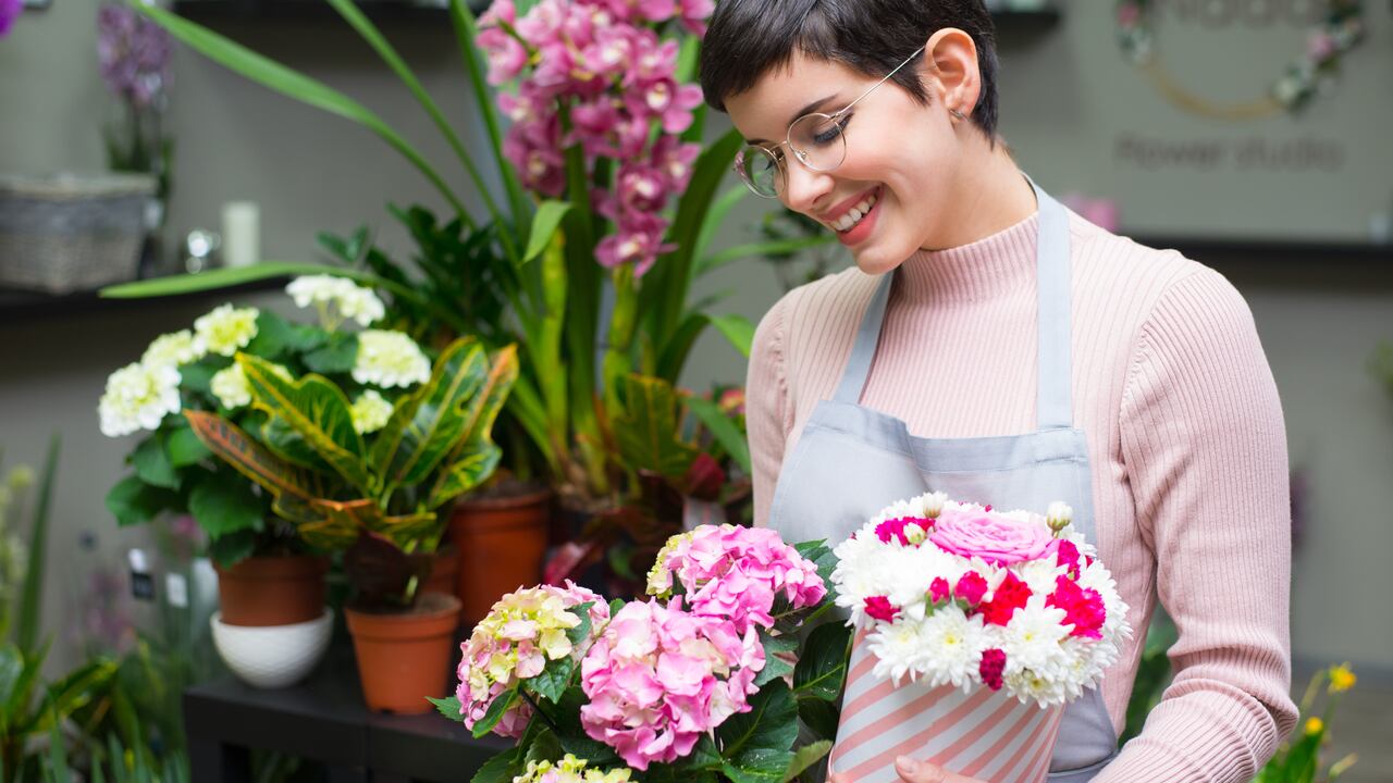 Young happy woman working in the flower shop.
