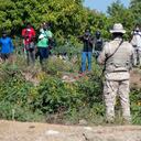 A Dominican soldier from the Specialized Land Border Security Corps (CESFRONT) observes Haitian citizens during a militarization operation on the border with Haiti closed by order of Dominican President Luis Abinader in Dajabon, Dominican Republic, on September 15, 2023. Dominican President Luis Abinader on Thursday announced the closure of the country's border with Haiti, escalating a diplomatic row over access to a shared river. (Photo by STRINGER / AFP)