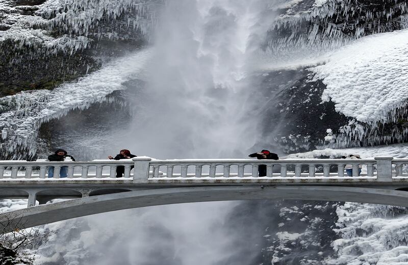 Nieve, una cascada y vegetación congelada son los atractivos a los que estos visitantes de Multnomah Falls, en Oregon, Estados Unidos, toman fotos. (AP)