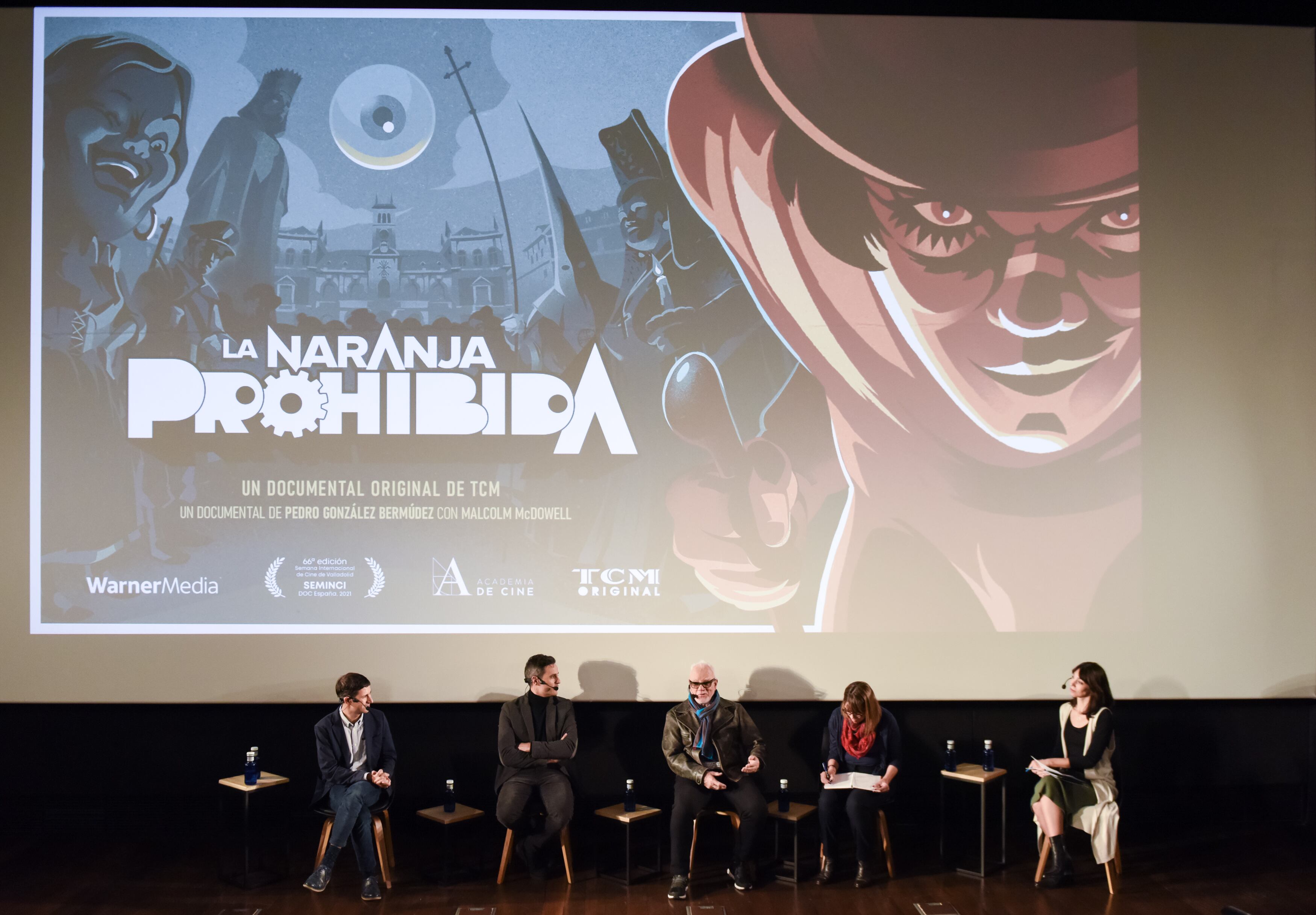 (De izquierda a derecha) El compositor y productor delegado, Guillermo Farre; el director del documental 'La naranja prohibida', Pedro González; el actor y protagonista de "La naranja mecánica" (1971), Malcolm McDowell; un traductor; y la coordinadora de comunicación de los canales de televisión TCM y TNT de WarnerMedia España, Patricia Cruzado, responden en rueda de prensa a la presentación del documental 'La naranja prohibida'
