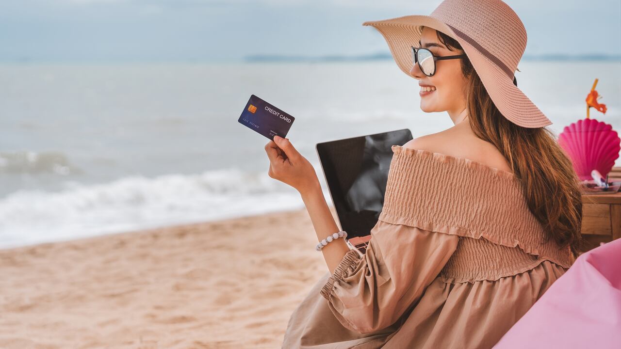 On vacation at Pattaya beach, asian traveler woman with floppy hat use credit card in luxury cafe.