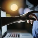 Disparo de una mano incorpórea que llega a través de la pantalla de un portátil para robar una tarjeta de crédito