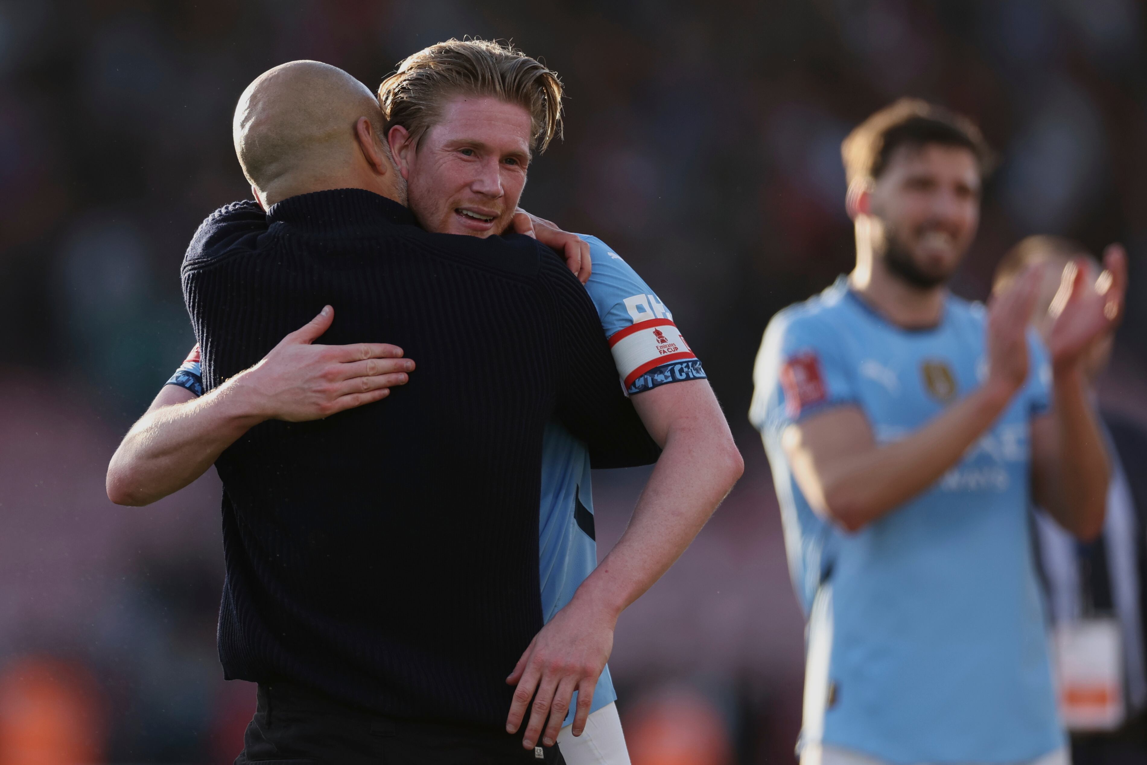 Manchester City's Kevin De Bruyne, center, celebrates with Manchester City's head coach Pep Guardiola, left, at the end of the English FA Cup quarterfinal soccer match between Bournemouth and Manchester City at the Vitality stadium in Bournemouth, England, Sunday, March 30, 2025. (AP Photo/Ian Walton)