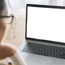 Vista de primer plano sobre el hombro de una estudiante con anteojos empresaria mirando una pantalla de maqueta en blanco vacía para publicidad, con videoconferencia virtual. Concepto de trabajo en línea de aprendizaje electrónico remoto.