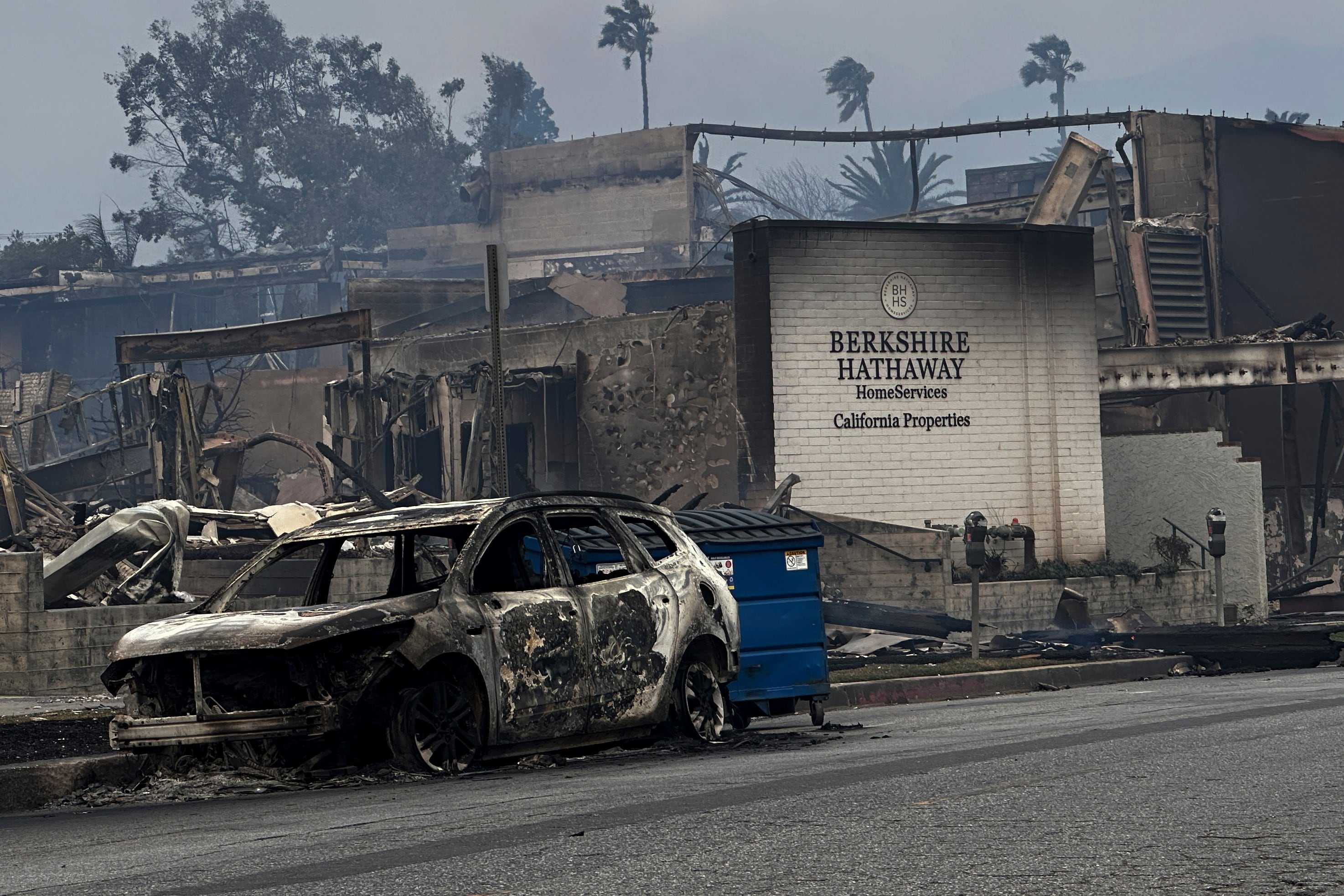 Fire-ravaged businesses and vehicles are left behind after the Palisades Fire swept through in the Pacific Palisades neighborhood of Los Angeles, Wednesday, Jan. 8, 2025. (AP Photo/Eugene Garcia)
