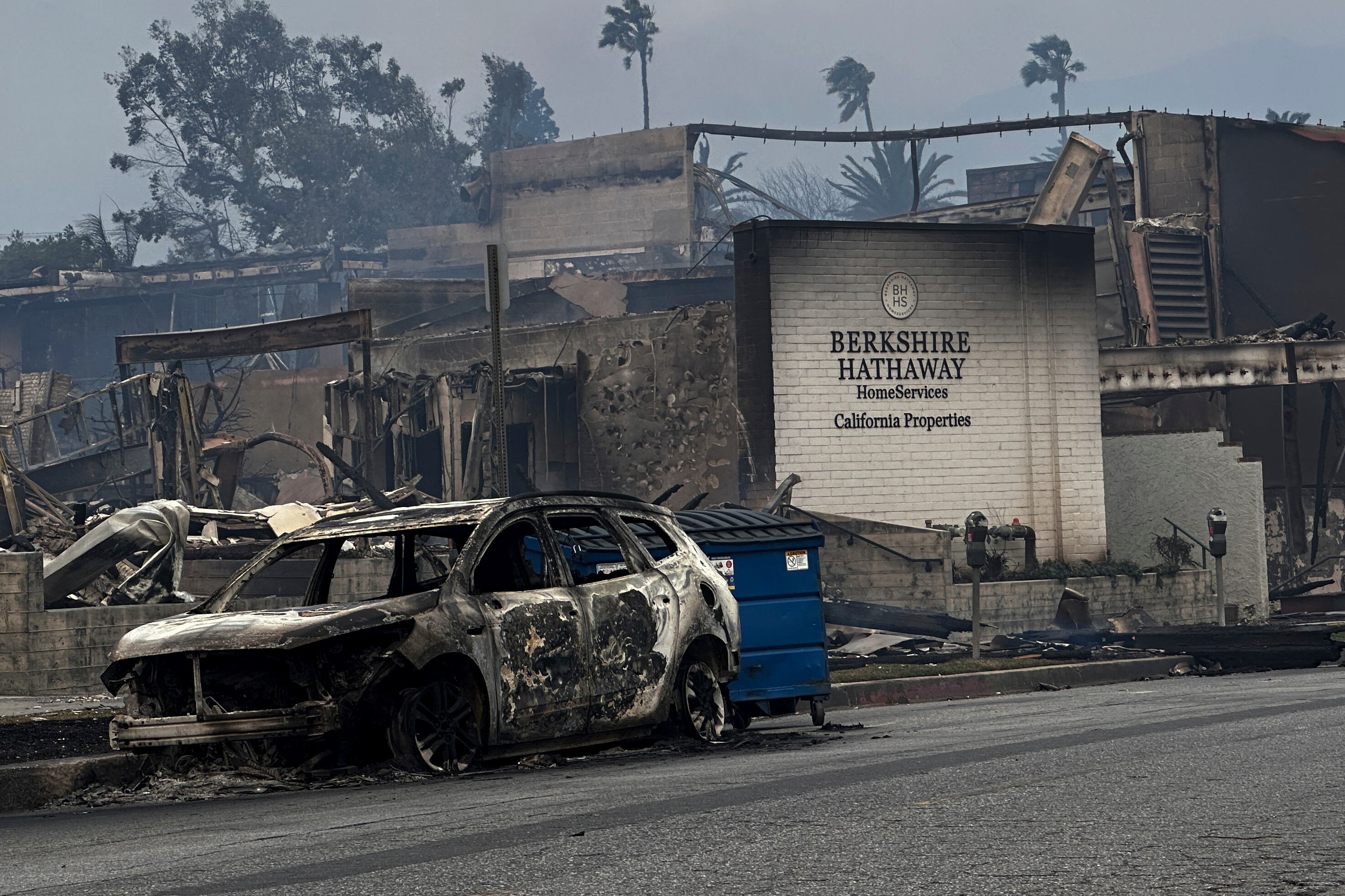 Fire-ravaged businesses and vehicles are left behind after the Palisades Fire swept through in the Pacific Palisades neighborhood of Los Angeles, Wednesday, Jan. 8, 2025. (AP Photo/Eugene Garcia)