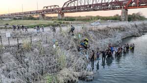 Las personas que cruzaron la frontera entre Estados Unidos y México buscan un paso a través de alambre de púas en el lado texano del Río Grande.