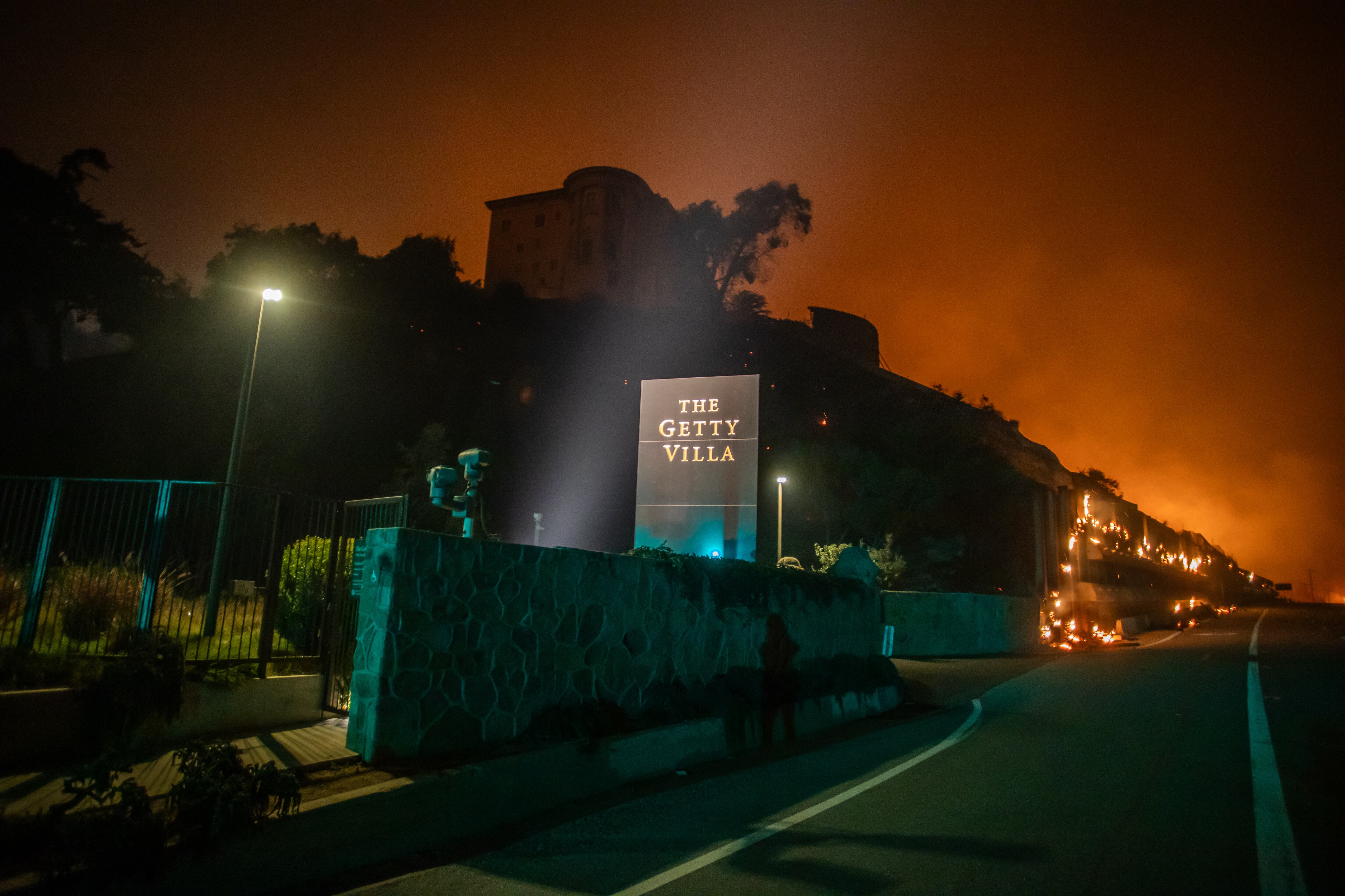 LOS ANGELES, CALIFORNIA - JANUARY 8: Flames from the Palisades Fire reach the grounds of the Getty Villa Museum on the Pacific Coast Highway amid a powerful windstorm on January 8, 2025 in Los Angeles, California.  The fast-moving wildfire has grown to more than 2900-acres and is threatening homes in the coastal neighborhood amid intense Santa Ana Winds and dry conditions in Southern California. (Photo by Apu Gomes/Getty Images)