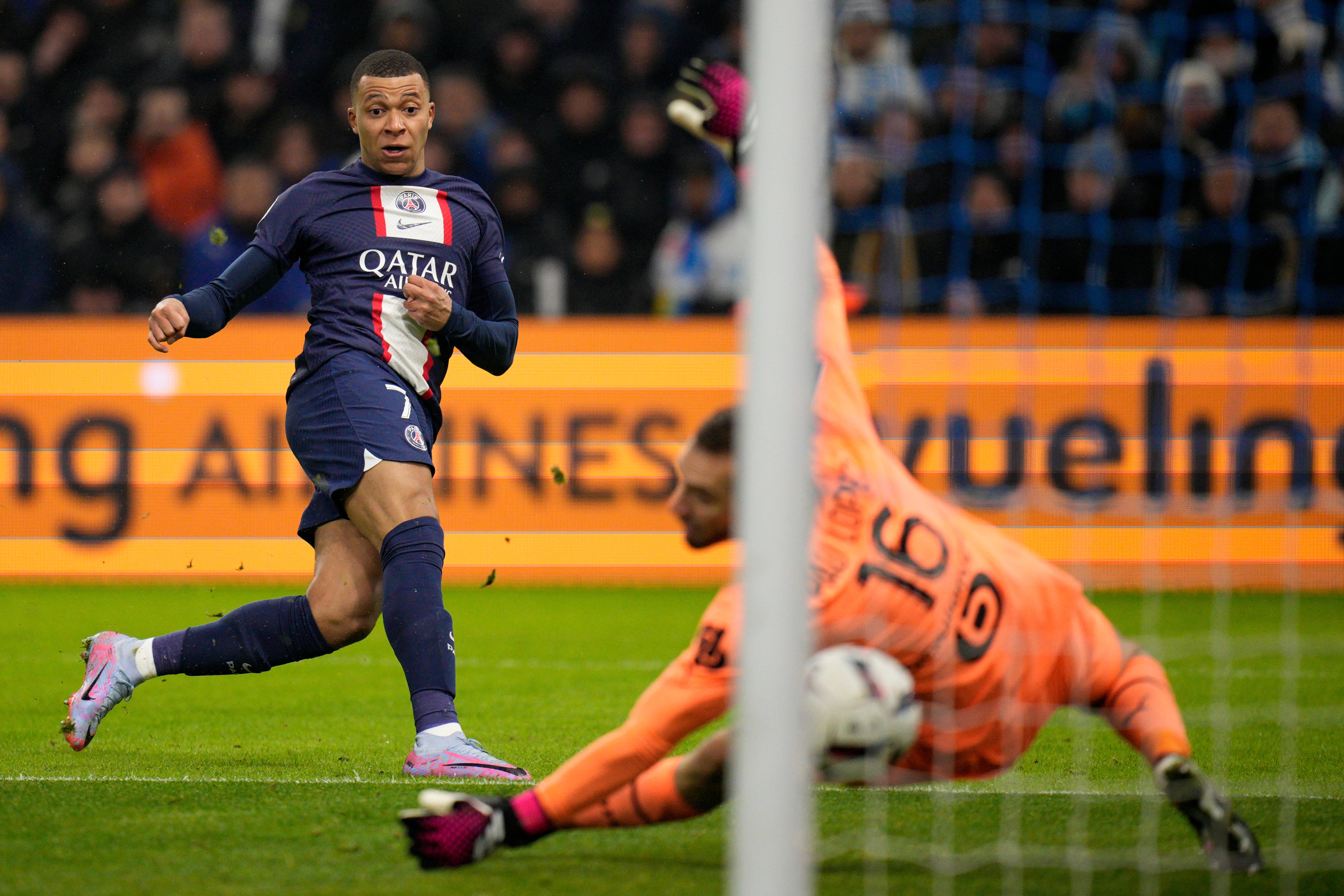 PSG's Kylian Mbappe, left, scores his side's third goal during the French League One soccer match between Marseille and Paris Saint-Germain at the Velodrome stadium in Marseille, southern France, Sunday, Feb. 26, 2023. (AP Photo/Daniel Cole)