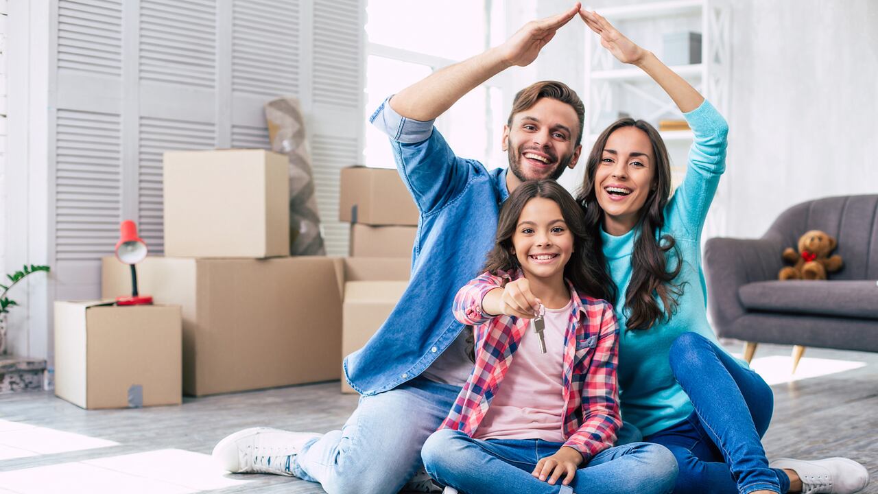 Mom and dad are imitating a roof of the house with their hands while their daughter holds keys from their new apartment in her hands. House moving concept.