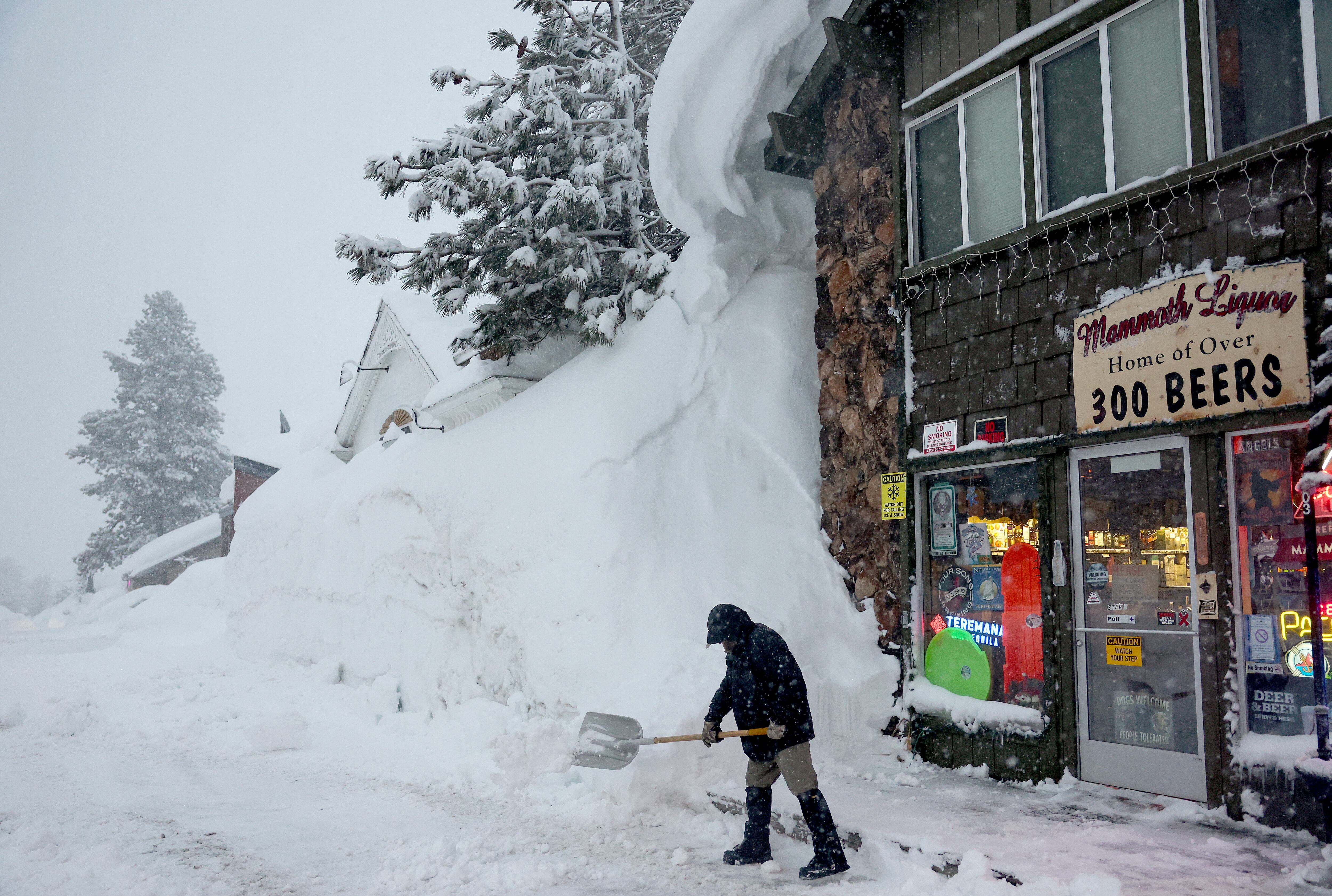 Spike Todd palas frente a su tienda cerca de bancos de nieve acumulados de tormentas anteriores durante otra tormenta de invierno en las montañas de Sierra Nevada el 10 de marzo de 2023 en Mammoth Lakes, California. Todd dijo: 'He vivido aquí 43 años y este se perfila como el invierno más grande que he visto en mi vida'. Las montañas de Sierra Nevada de California están siendo golpeadas por fuertes nevadas en elevaciones más altas, lo que eleva aún más los niveles de la enorme capa de nieve. Las comunidades de las montañas que aún se están recuperando de tormentas anteriores en elevaciones más bajas se enfrentan a posibles inundaciones debido a la escorrentía de lluvia de la décima tormenta fluvial atmosférica del estado. El presidente Joe Biden aprobó la solicitud de emergencia presidencial del gobernador Gavin Newsom en respuesta a las recientes tormentas que afectaron a California. Mario Tama/Getty Images/AFP (Foto de MARIO TAMA/GETTY IMAGES NORTH AMERICA/Getty Images vía AFP)